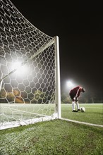 USA, California, Ladera Ranch, goalie on illuminated soccer field at night.