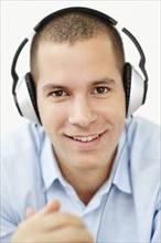 South Africa, Young man wearing earphones and looking at camera, studio shot. Photo : momentimages