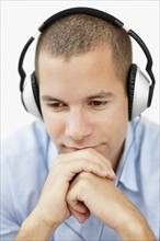 South Africa, Young man wearing earphones and looking away, studio shot. Photo : momentimages