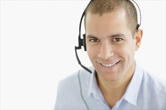 South Africa, Portrait of smiling young man wearing headset, studio shot. Photo : momentimages