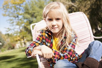 USA, Utah, outdoor portrait of blonde girl (6-7) sitting on deck chair. Photo : Tim Pannell