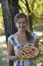 USA, Colorado, Cheerful young woman holding pie. Photo : John Kelly
