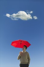 Man holding umbrella under cloud.