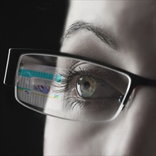 Reflection of graph in businesswoman's glasses.