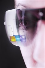 Reflection of chemical flasks in female scientists glasses.