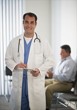 USA, New Jersey, Jersey City, Portrait of doctor holding medical results with male patient in background.