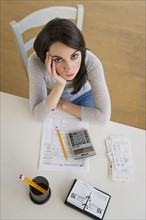Young woman doing taxes and looking at camera.