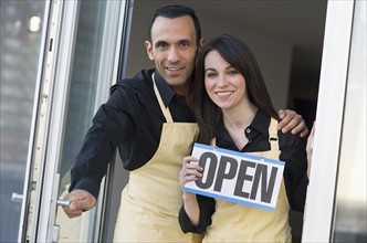 Couple holding open sign.