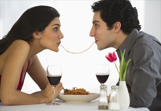 Happy couple eating spaghetti together.