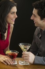 Young couple having drinks and flirting, studio shot.