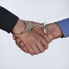 Handshake with handcuffs, studio shot. Photo : Daniel Grill