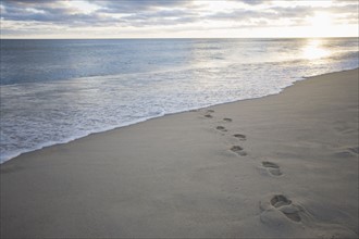 USA, Massachusetts, Cape Cod, footprints on beach at sunset. Photo : Chris Hackett