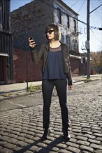 USA, New York City, Brooklyn, woman in street using phone. Photo : Shawn O'Connor