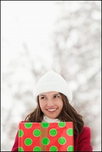 USA, Utah, Lehi, Young woman holding Christmas gift outdoors. Photo : Mike Kemp