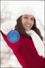 USA, Utah, Lehi, Portrait of young woman holding Christmas bauble outdoors. Photo : Mike Kemp