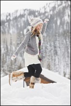 USA, Utah, Salt Lake City, young woman walking through snow in resort. Photo : Mike Kemp