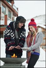 USA, Utah, Salt Lake City, couple warming hands over burner in ski resort. Photo : Mike Kemp