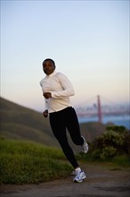 USA, California, San Francisco, Woman jogging, Golden Gate Bridge in background. Photo : Noah