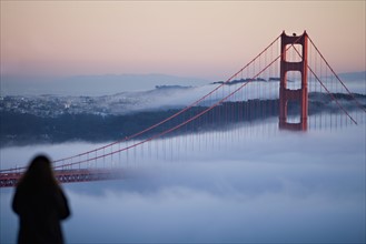 USA, California, San Francisco, Woman watching Golden gate Bridge in fog. Photo : Noah Clayton