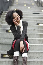 USA, Washington State, Seattle, young woman sitting on steps and talking on mobile phone. Photo :