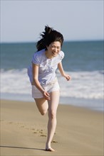 USA, California, Point Reyes, Young woman running on beach. Photo : Noah Clayton