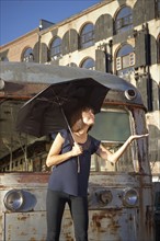 USA, New York City, Brooklyn, woman with umbrella checking for rain. Photo : Shawn O'Connor