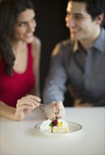 Young happy couple sharing dessert, studio shot.