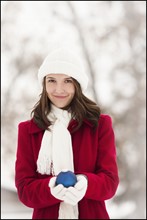 USA, Utah, Lehi, Portrait of young woman holding Christmas bauble outdoors. Photo : Mike Kemp