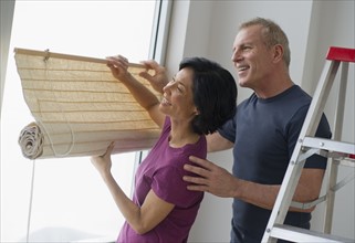 Mature couple hanging blinds.