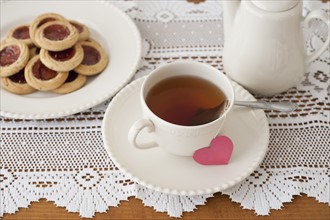 Heart shaped biscuit with cup of tea.