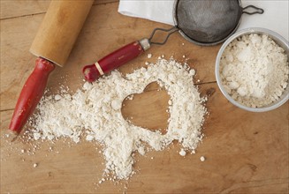 Heart shape in flour with baking utensils.