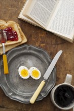 Boiled eggs and toast on table with book.