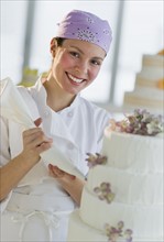Portrait of happy young woman decorating wedding cake.