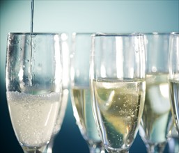 Close up of champagne flutes on blue background. Photo : Jamie Grill Photography