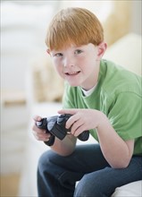 Portrait of boy (8-9) playing video game. Photo : Jamie Grill Photography