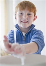 Portrait of boy (8-9) washing hands. Photo : Jamie Grill Photography