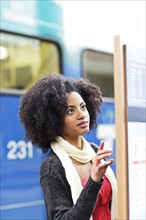 USA, Washington State, Seattle, young woman looking at arrival departure board. Photo : Take A Pix