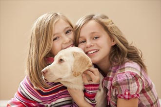Portrait of two girls (10-11) embracing Labrador . Photo : Mike Kemp