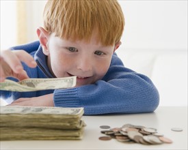 Portrait of boy (8-9) counting money. Photo : Jamie Grill Photography