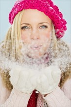 Studio portrait of young woman blowing snow. Photo : Daniel Grill
