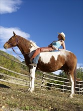 USA, Colorado, Cowgirl relaxing with horse on ranch. Photo : John Kelly