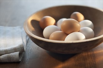 Bowl of raw eggs on table.