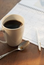 Cup of coffee beside calendar.