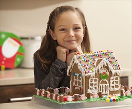Portrait of girl (6-7) by gingerbread house. Photo : Mike Kemp