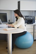 Business woman sitting on fitness ball.