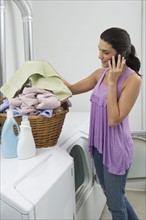 Woman doing laundry and talking on phone.