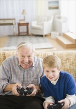 Grandfather and grandson (8-9) playing video games. Photo : Jamie Grill Photography