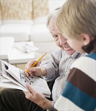 Grandfather and grandson (8-9) doing crossword. Photo : Jamie Grill Photography