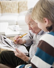 Grandfather and grandson (8-9) doing crossword. Photo : Jamie Grill Photography