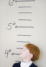 Boy (8-9) measuring height against chart. Photo : Jamie Grill Photography